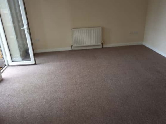 This is a photo of a living room after it has been cleaned. The room is empty and has a brown carpet that has been steam cleaned works carried out by Beddington Carpet Cleaning